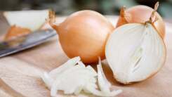 A white onion chopped in half on a wooden table outdoors.