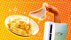 A hand coming out of a freezer and pouring gravy onto mashed potatoes.