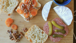 A sandwich on a cutting board surround by charcuterie. 